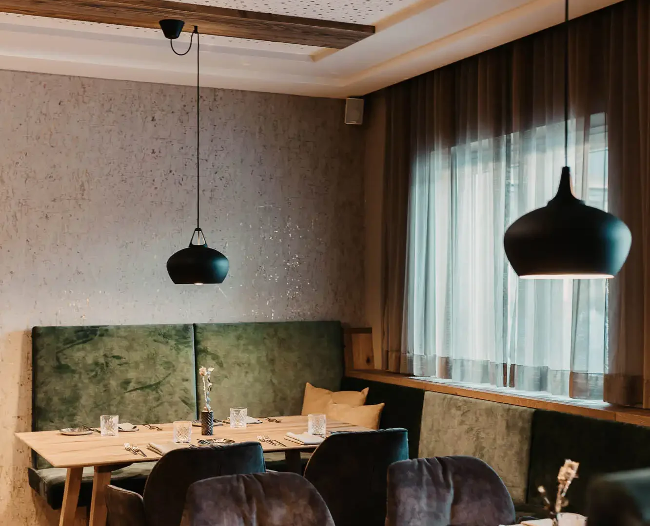 Cosy restaurant area at Hofgut Wagrain with stylish furnishings, soft upholstery and lovingly laid tables - an Alpine feel-good atmosphere to enjoy.