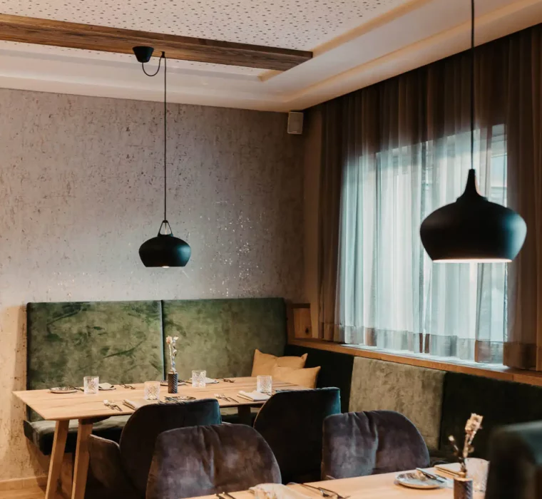 Cosy restaurant area at Hofgut Wagrain with stylish furnishings, soft upholstery and lovingly laid tables - an Alpine feel-good atmosphere to enjoy.
