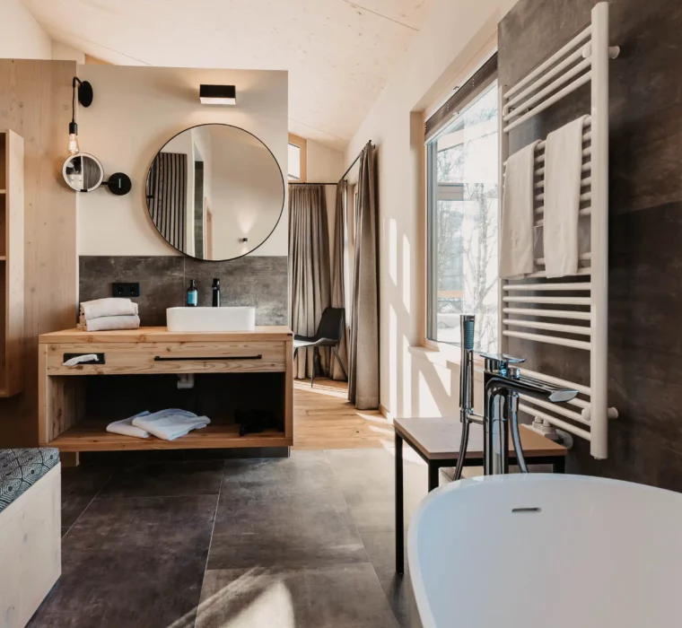 Modern design meets alpine charm - your stylish bathroom at Hofgut Wagrain with warm wooden accents and a view of nature.