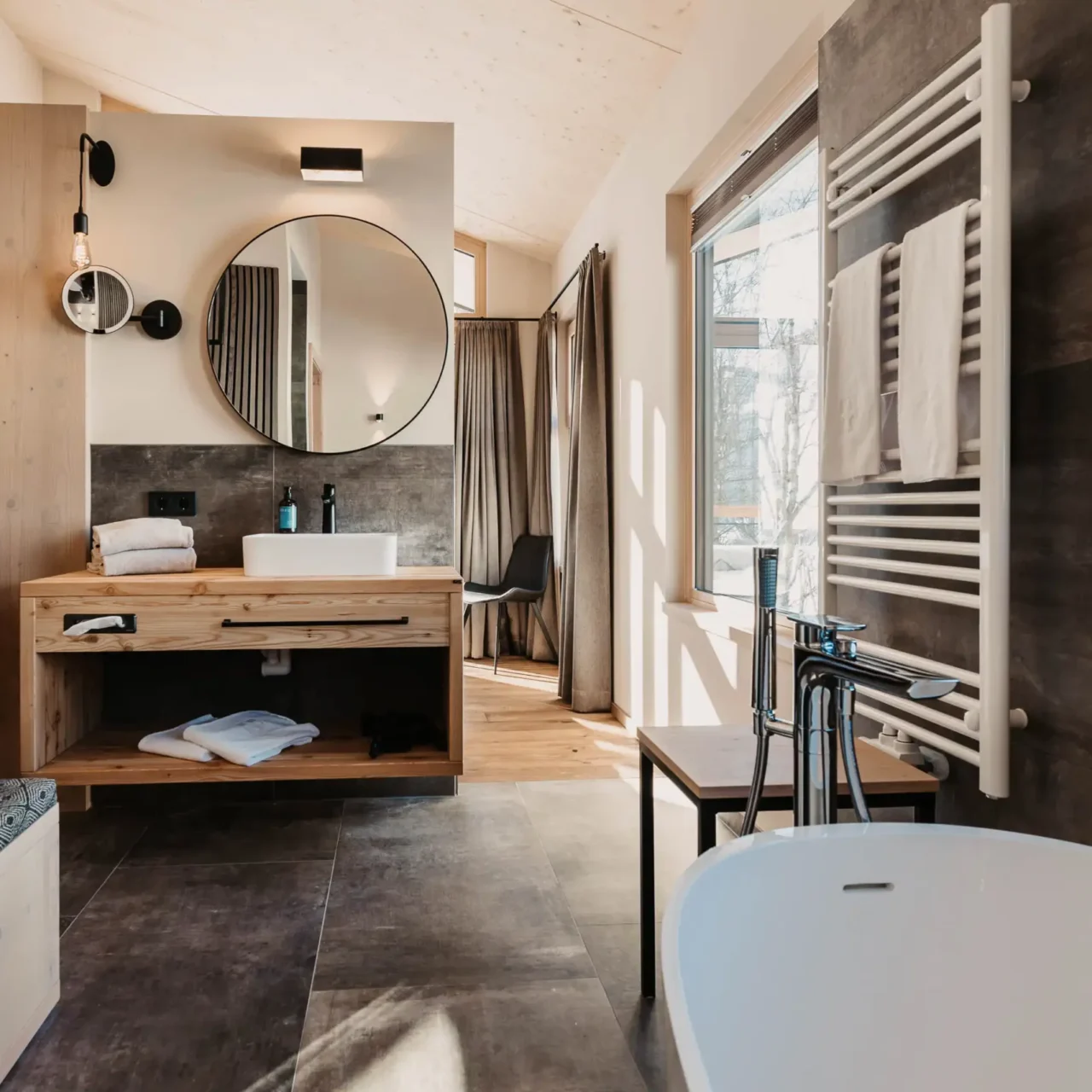 Modernes Design trifft alpinen Charme – Ihr stilvolles Badezimmer im Hofgut Wagrain mit warmen Holzakzenten und Blick in die Natur.