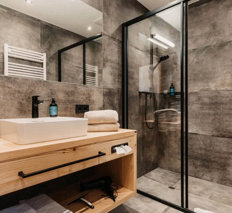 Edles Design und natürliche Materialien: Das stilvolle Badezimmer vereint Funktionalität mit modernem alpinen Charme.