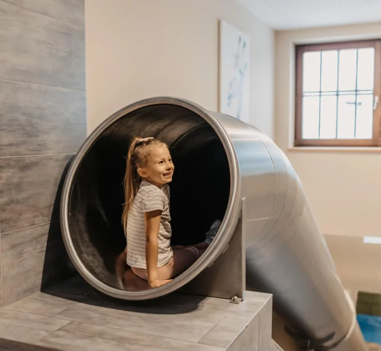 With a smile into the adventure: Happy sliding on the indoor slide at Hofgut Wagrain - fun and action for little explorers.