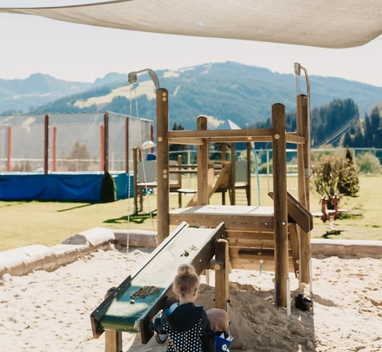 Outdoor-Spielplatz Wagrain – Sandbereich und Wasserrinne für Kleinkinder.