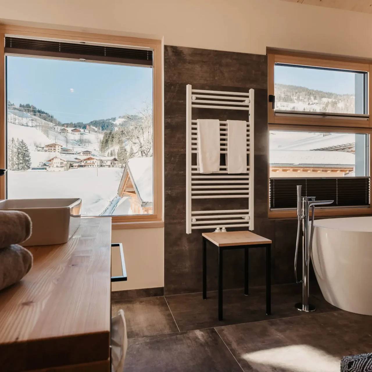 Modern bathroom at Hofgut Wagrain with free-standing bathtub and views of the snow-covered winter landscape of the Salzburg Alps.