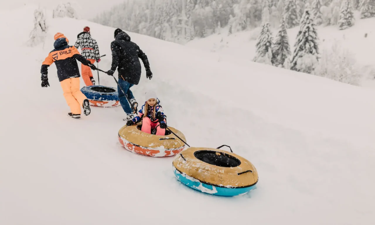 Tobogganing fun in the snow - children on a snowtubing adventure with the family in the snowy winter paradise of Hofgut Wagrain.