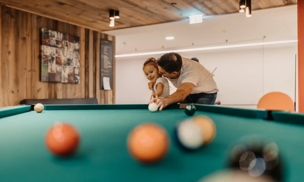 Having fun playing pool together - father and daughter enjoy valuable family time in the Games Area at Hofgut Wagrain.