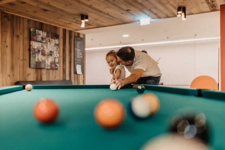 Gemeinsamer Spaß beim Billard – Vater und Tochter genießen wertvolle Familienzeit in der Games Area des Hofgut Wagrain.