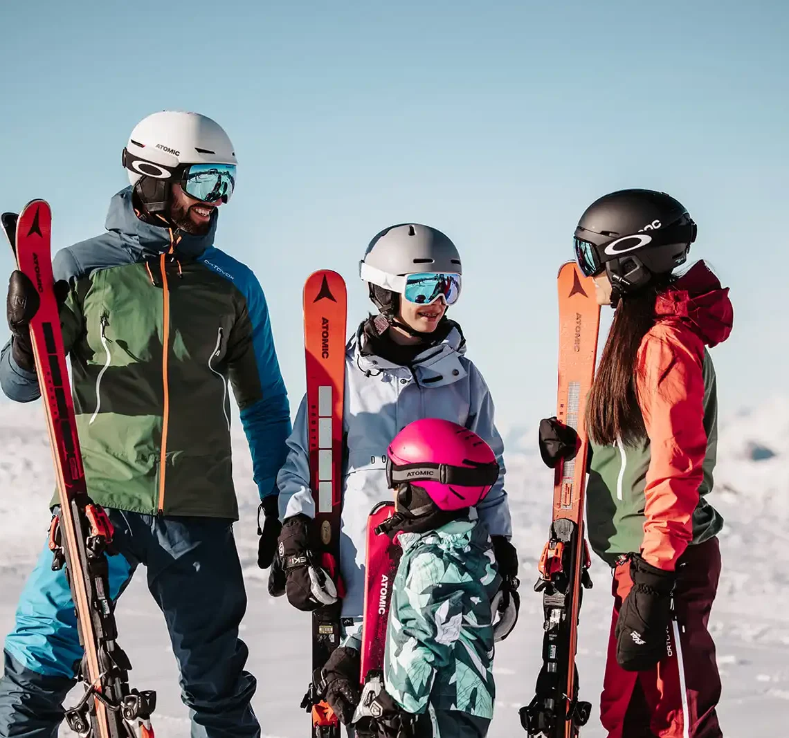 Winterglück für Groß und Klein – lachende Familie mit Skiern vor traumhafter Alpenkulisse im Hofgut Wagrain.