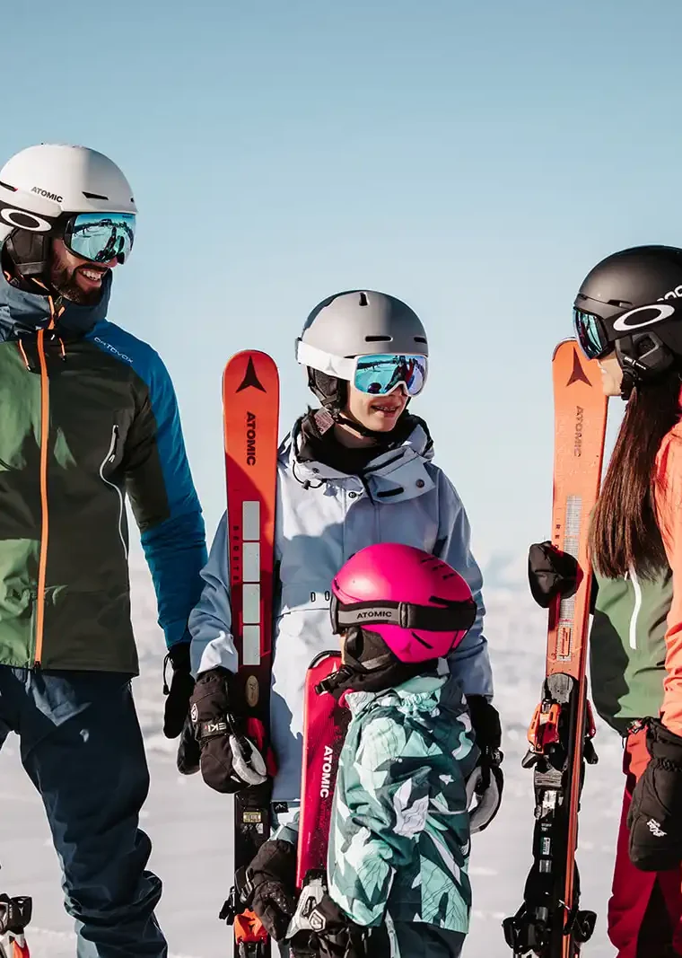 Winterglück für Groß und Klein – lachende Familie mit Skiern vor traumhafter Alpenkulisse im Hofgut Wagrain.