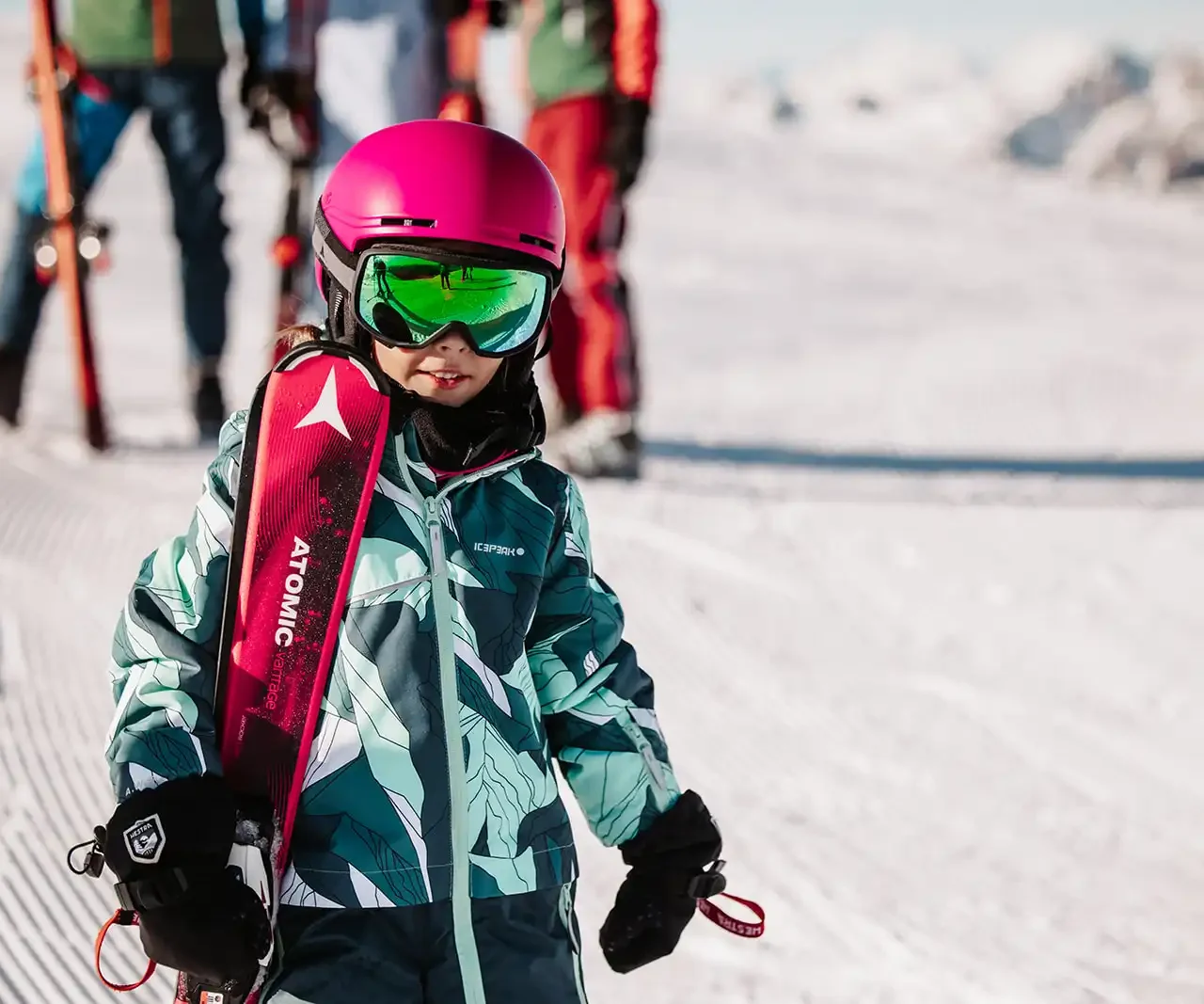 Kleines Kind mit Skiausrüstung vor winterlicher Bergkulisse – bereit für den Skitag im Familienresort Hofgut Wagrain.