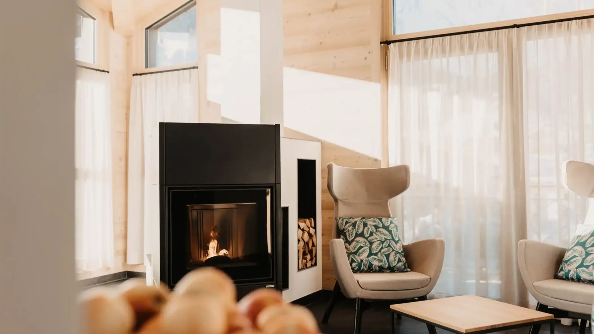 Teelounge im Adults-only Spa des Hofgut Wagrain – stilvolle Ohrensessel am knisternden Kamin, warme Atmosphäre und Ausblick auf die verschneiten Berge.