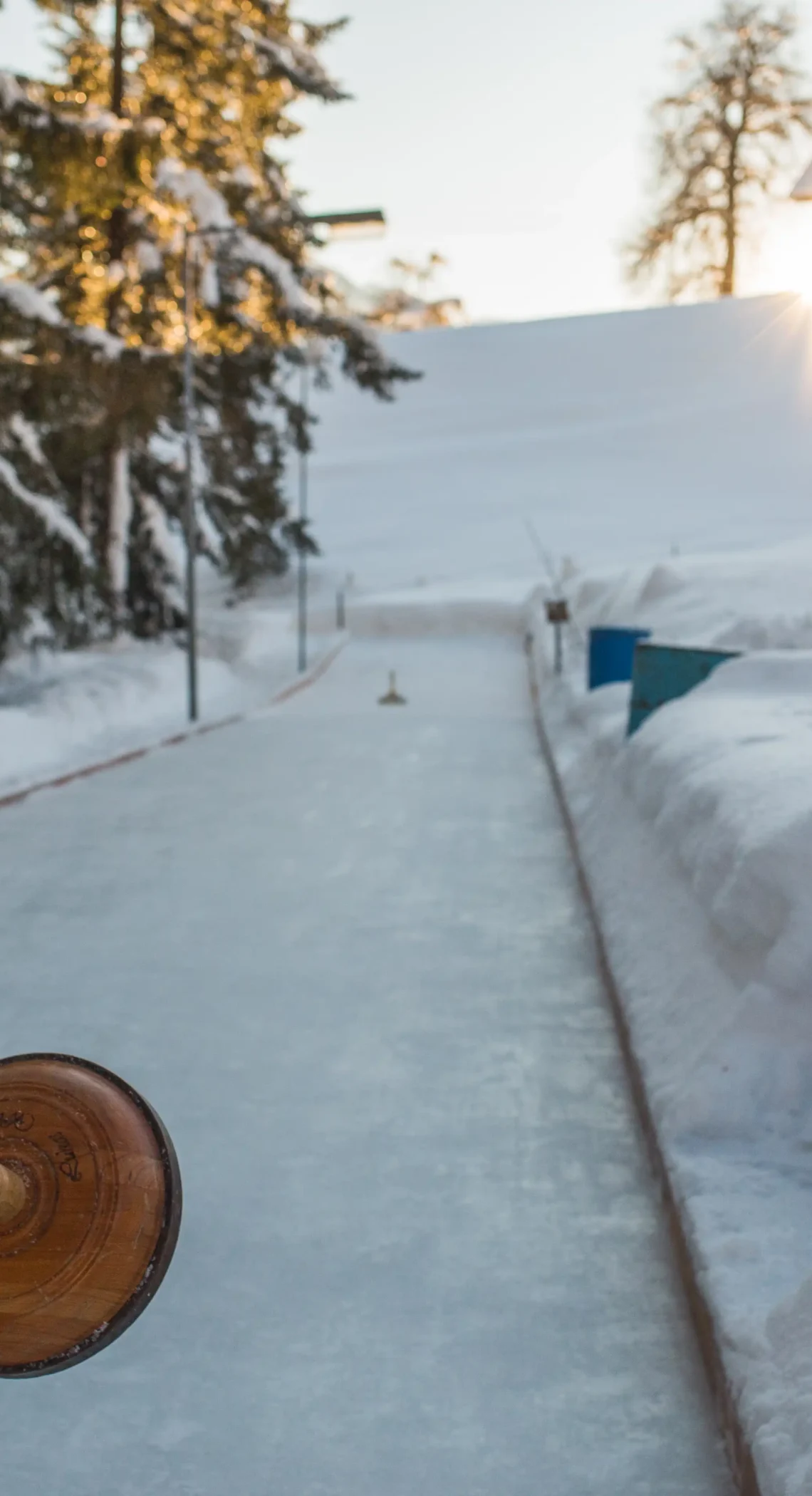 Tradition trifft Wintervergnügen – Eisstockschießen inmitten verschneiter Berglandschaft bei Sonnenuntergang.