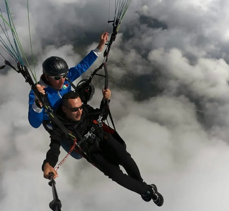 Zwei Personen beim Tandem-Paragliding hoch über einer Wolkendecke – actionreich, frei und mit großartiger Aussicht.