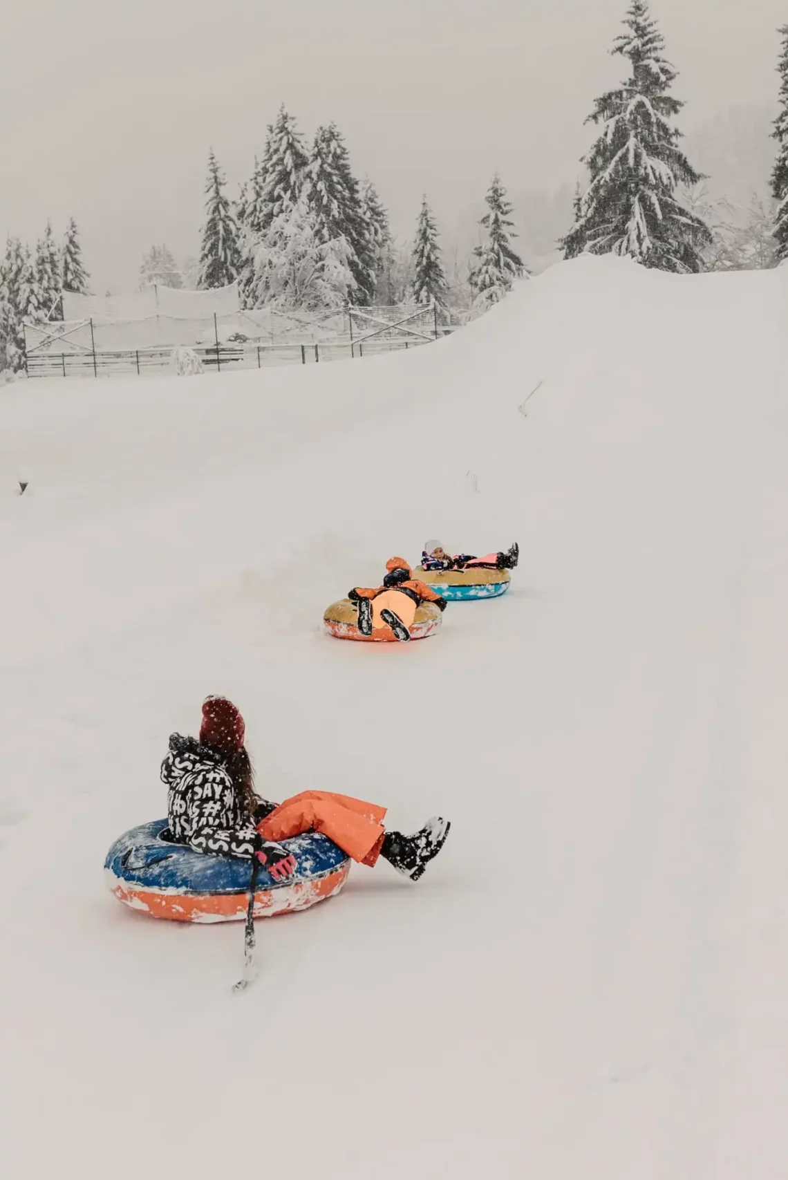 kinder beim snowtubing auf verschneiter bahn am hofgut wagrain