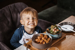 lächelndes kind beim essen mit currywurst und salat im restaurant