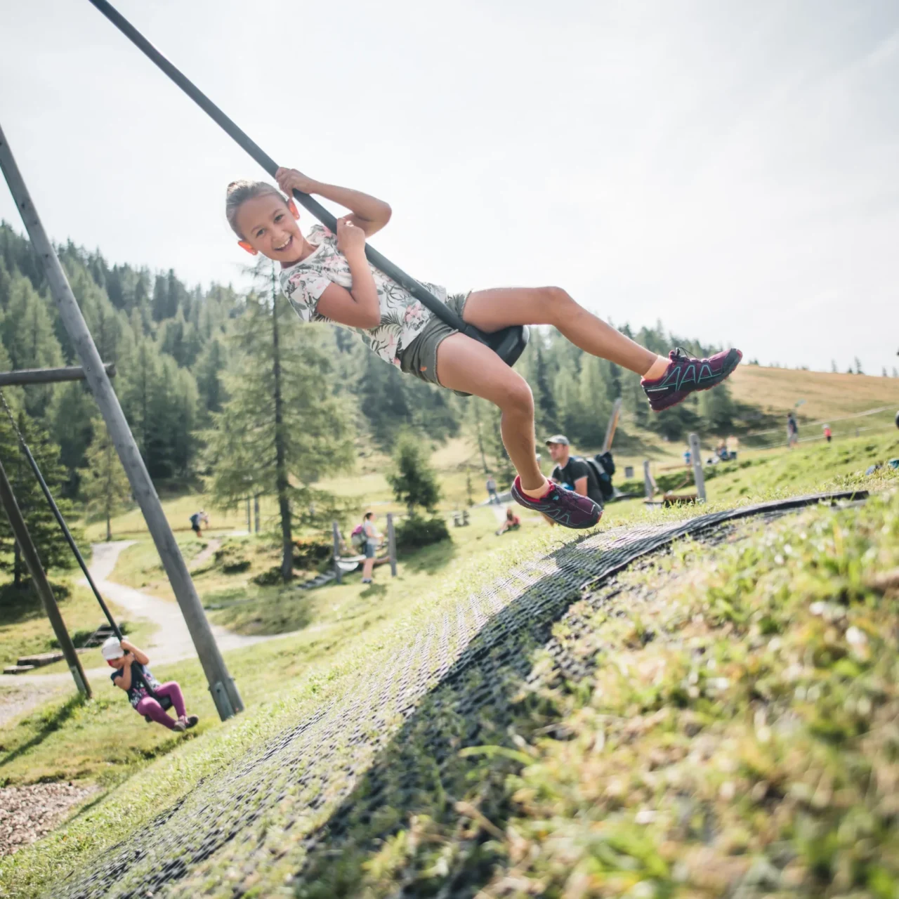 Mädchen auf einer Seilschaukel am Bergspielplatz beim Wagraini's Grafenberg.