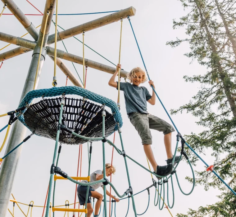 Kind klettert auf einem Abenteuerspielplatz mit Seilen und Holzstrukturen am Geisterberg.
