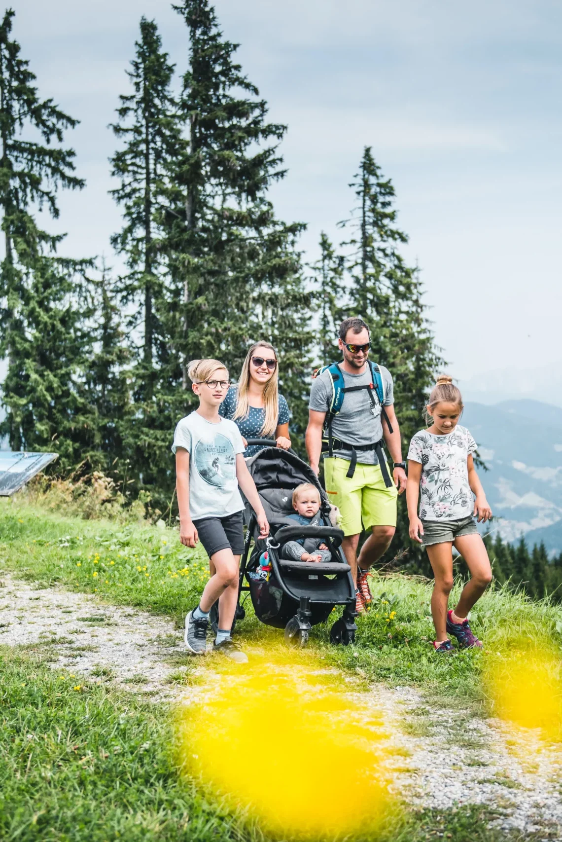 Familie mit Kinderwagen wandert auf einem Panoramaweg am Grafenberg mit Blick auf die Alpen