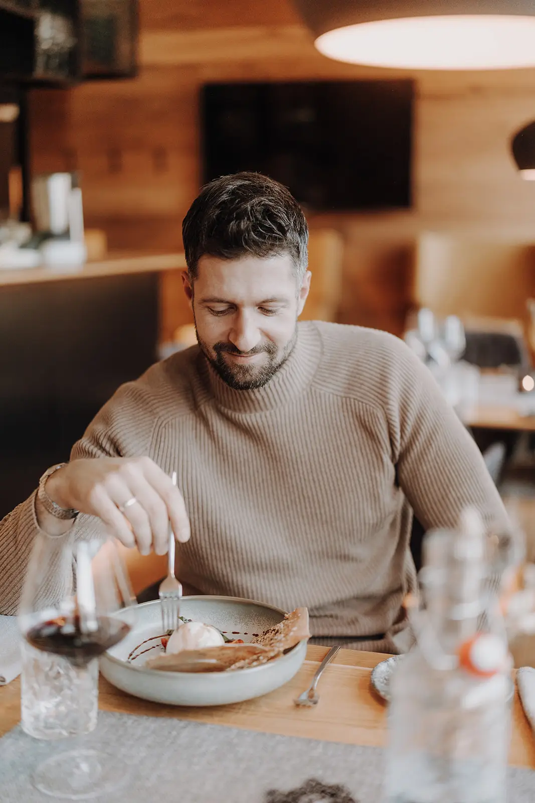 Mann genießt ein Dessert bei gemütlicher Atmosphäre im Restaurant des Hofgut Wagrain.