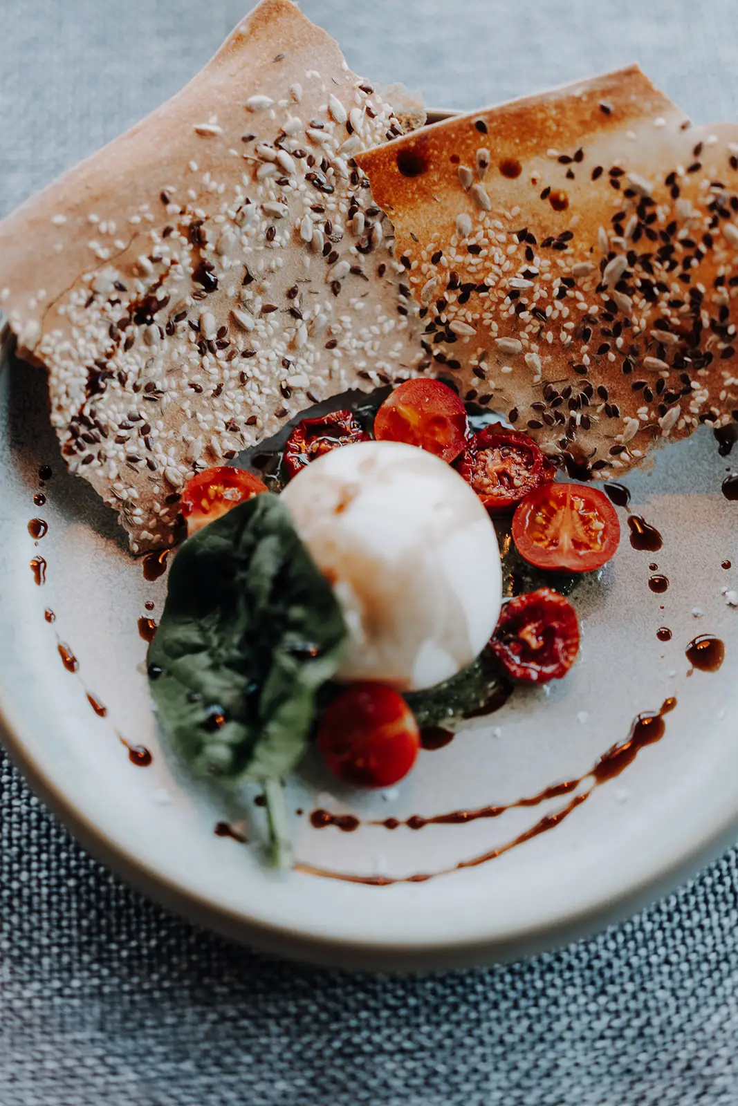 Burrata mit Kirschtomaten, Basilikum und Balsamico, serviert mit knusprigem Saatenbrot im Restaurant Vamoos im Hofgut Wagrain.