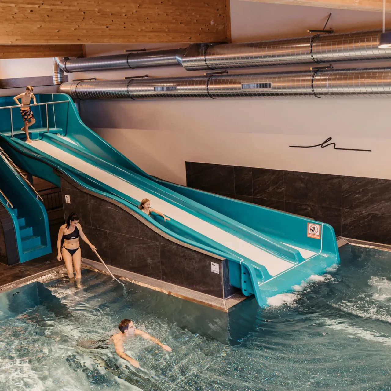 Badespaß für die ganze Familie im warmen Indoor-Pool mit Rutsche – gemeinsames Lachen und Leichtigkeit im Hofgut Wagrain.