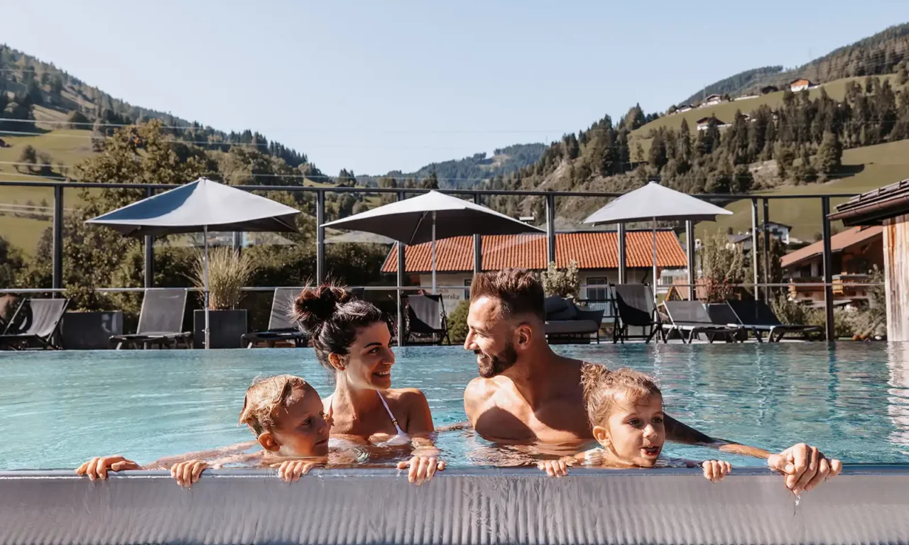 Familie im Sommerurlaub im Rooftop Pool vom Hofgut Wagrain.