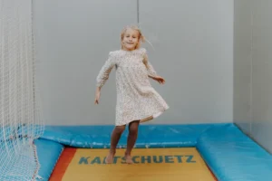 Ein Kind hüpft hoch auf dem Trampolin in der Indoor-Spielewelt des Hofgut Wagrain.