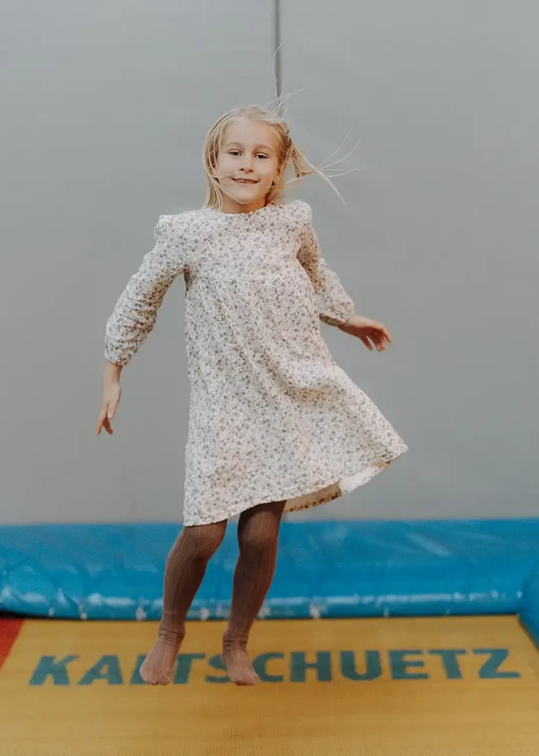 Ein Kind hüpft hoch auf dem Trampolin in der Indoor-Spielewelt des Hofgut Wagrain.