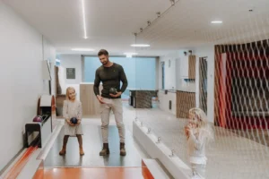 Ein Vater und seine Tochter schauen sispielen gemeinsam auf der Kegelbahn im Hofgut Wagrain. Der Vater hält eine Kegel in der Hand.