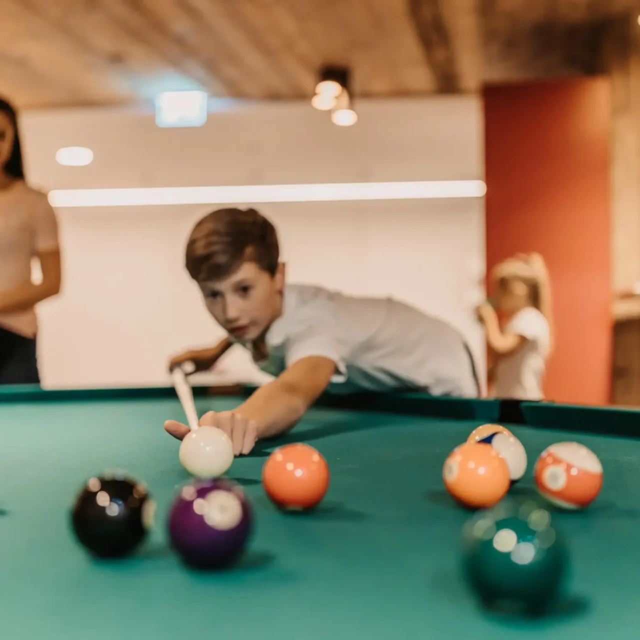 Spielspaß für Groß und Klein: Familienzeit am Billardtisch in der stylischen Games Area des Hofgut Wagrain – gemeinsam lachen, zielen und genießen.